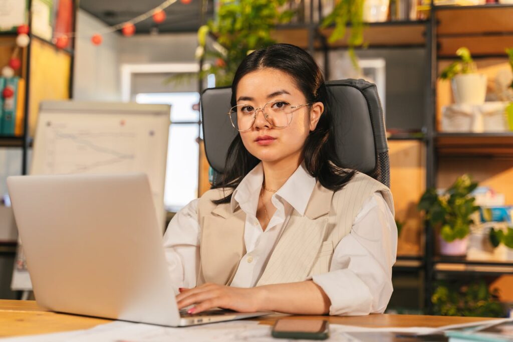 pexels photo 8278979 Confident businesswoman with glasses focusing on work using a laptop in a modern office setting.
