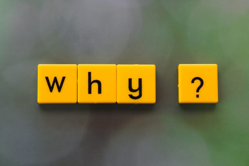 pexels photo 36507933 36507933 Yellow letter tiles spelling 'why?' create a thought-provoking scene on a green blurred background.