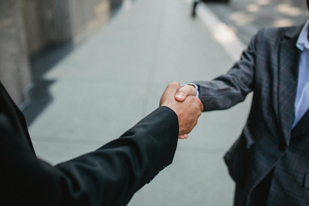 pexels photo 4963359 4963359 Close-up of two businessmen shaking hands outside, symbolizing partnership and agreement.