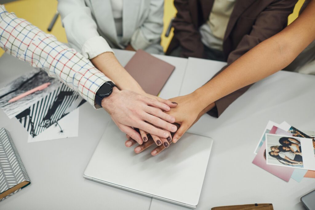 pexels photo 7495190 7495190 Close-up of diverse business team joining hands over a laptop, symbolizing teamwork and unity.