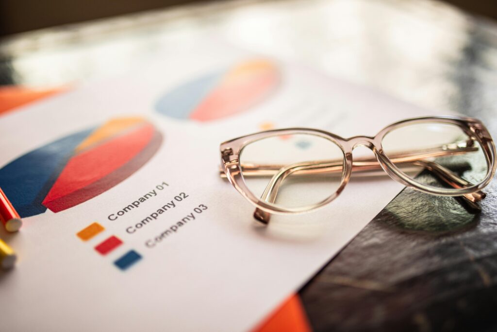 pexels photo 7948004 7948004 Close-up of eyeglasses on a table with colorful business charts.
