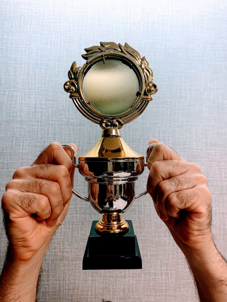 pexels photo 5286746 5286746 Close-up of hands holding a shiny trophy symbolizing achievement and victory.
