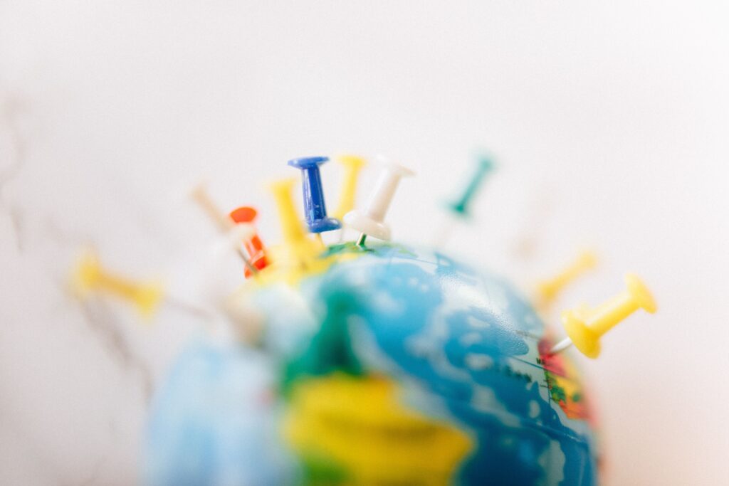 pexels photo 7236028 7236028 Vibrant close-up of a globe marked with multicolored push pins on a white background.
